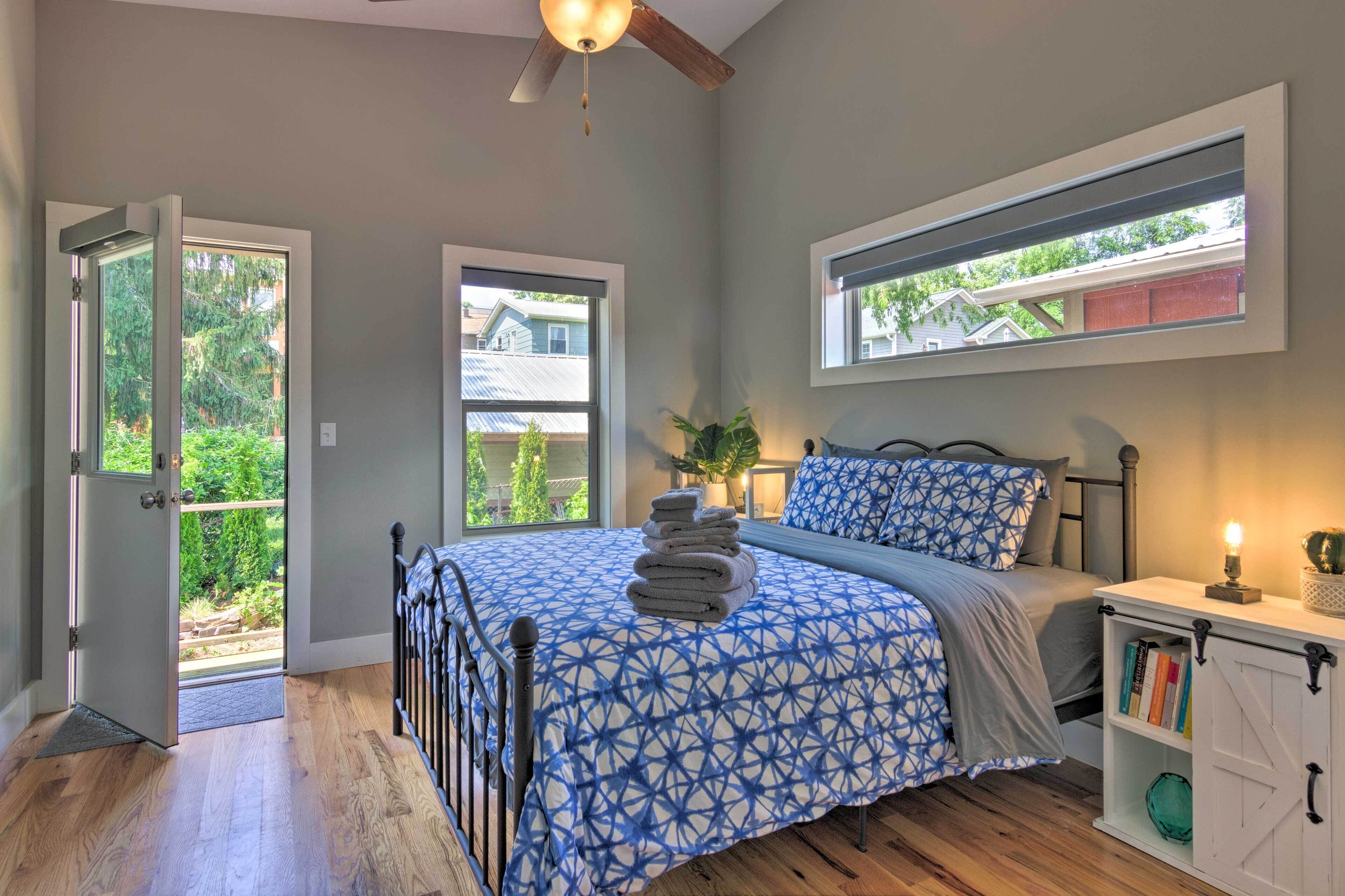 Une chambre à coucher comprenant un lit, une fenêtre, un ventilateur de plafond et une porte donnant sur un balcon.