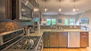 A modern kitchen with a stainless steel stove, a dishwasher, and a large island with a sink. - Modern Asheville Greenway Residence w/ 2 Decks! (Asheville)