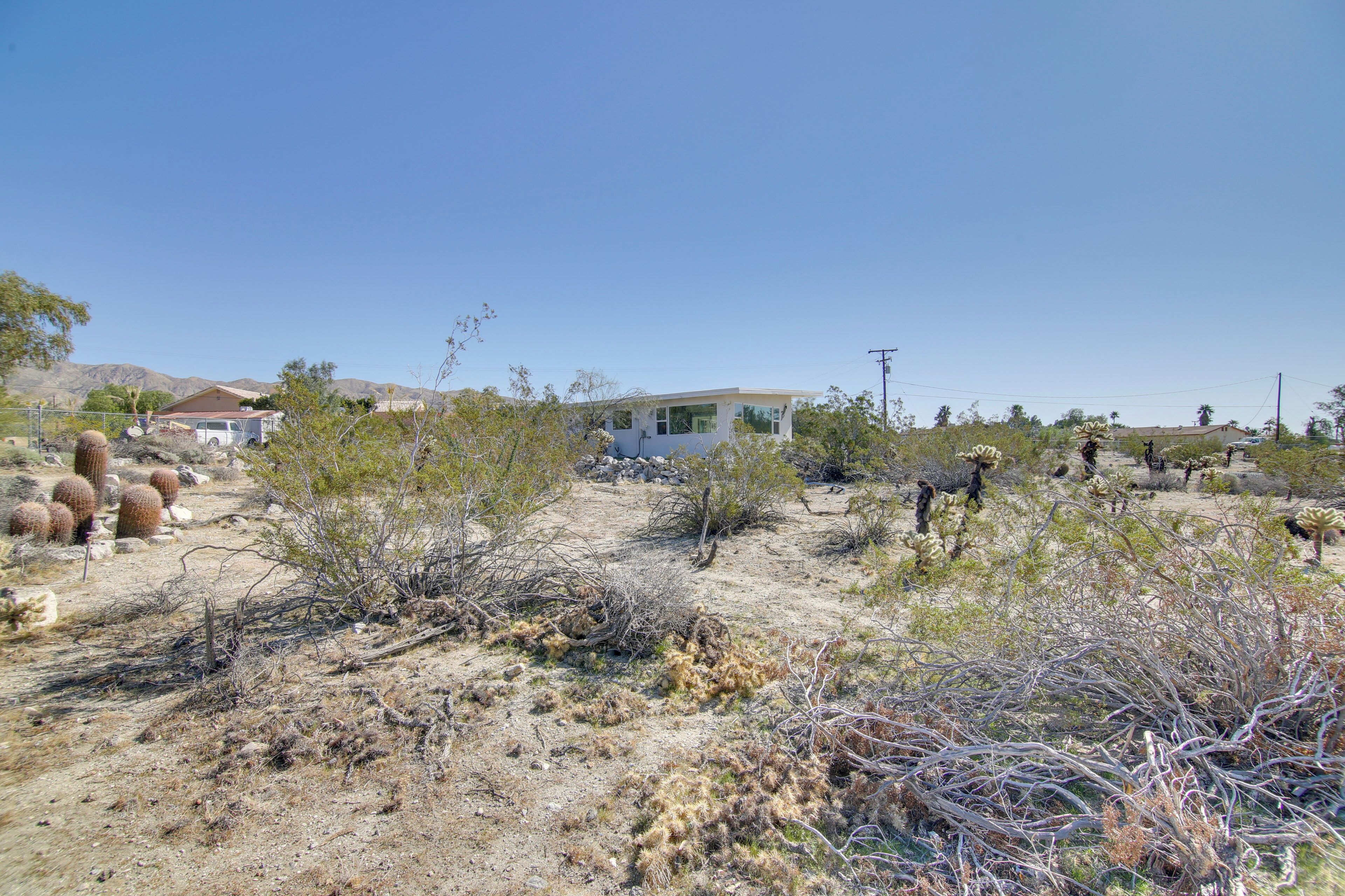 A desert landscape with sparse vegetation, a white building, and a few cacti.