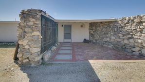 A building with a stone exterior, a metal gate, and a paved entrance. - Patio & Views: Eccentric Desert Hot Springs Home (Desert Hot Springs)