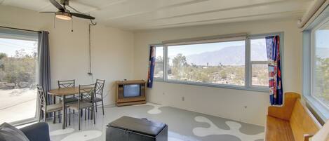 A spacious living area with a sofa, a coffee table, a TV, and a dining table with chairs.