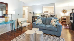 A living room with a blue sofa, two round side tables, a wooden coffee table, and a patterned rug. - Mount Pleasant Condo - Near Charleston & Beaches! (Mount Pleasant)