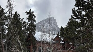 Un paisaje nevado con una cabaña de madera y una montaña al fondo.