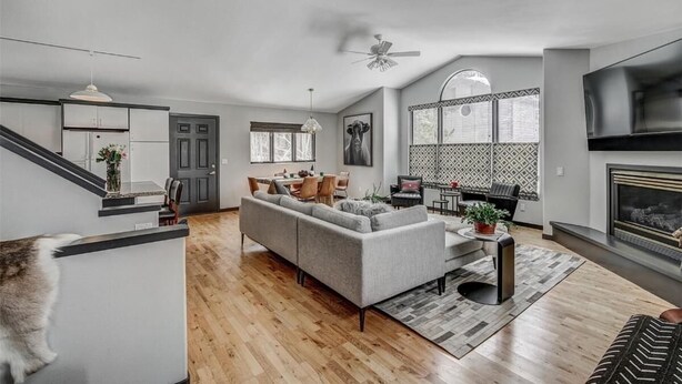 Una sala de estar moderna con un sofá seccional gris, una chimenea y un comedor con mesa y sillas.