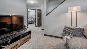 Una sala de estar moderna con una televisión de pantalla plana, un sofá y una lámpara.