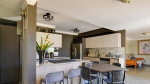 A modern kitchen with a central island, bar stools, and a dining table. - Walk to Isla Verde Beach! Home w/ Heated Pool (Carolina)