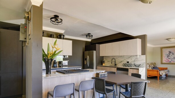 Una cocina moderna con una isla central, taburetes de bar y una mesa de comedor.
