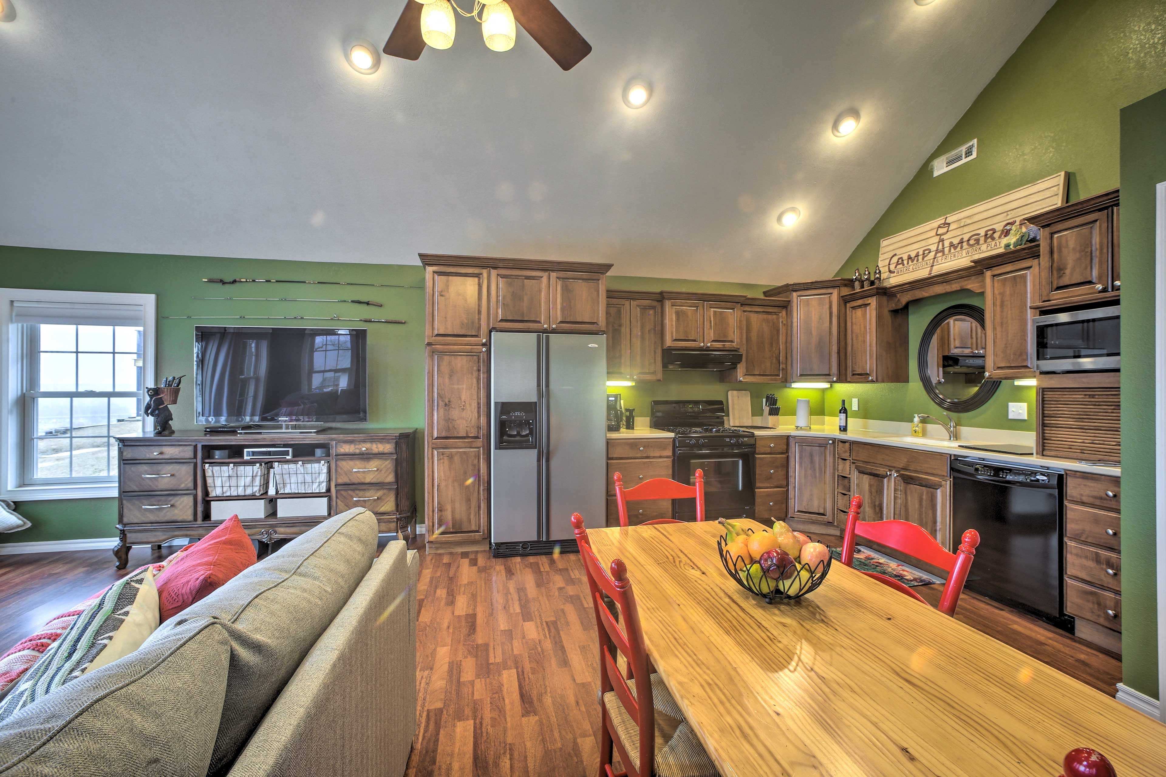 A kitchen with wooden cabinets, a refrigerator, a stove, and a dining table with chairs.