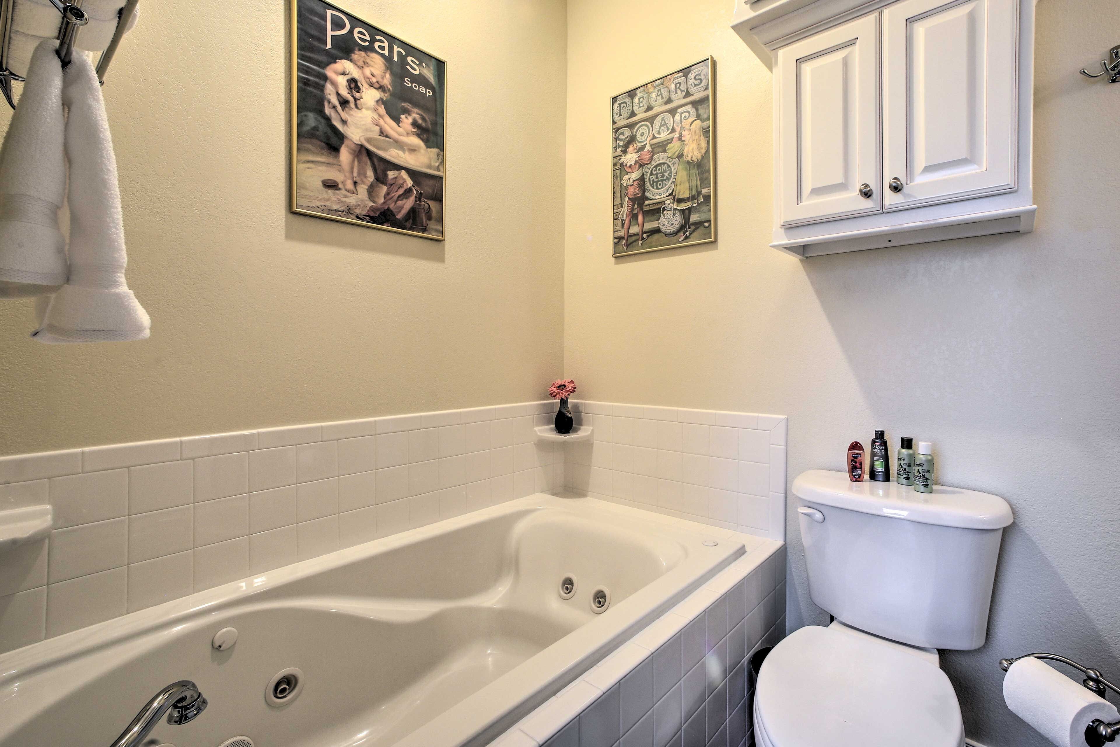 A bathroom with a bathtub, toilet, and two framed posters on the wall.