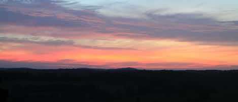A sunset over a hilly landscape with a clear sky.