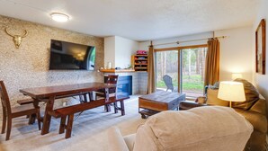 A living room with a wooden dining table, benches, a sofa, a TV mounted on the wall, and a fireplace. - Beautiful Breck Townhome w/ Pool: 1 Mi to Main St! (Breckenridge)