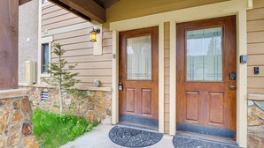 A wooden front door with a glass panel, a stone wall, and a small tree. - Beautiful Breck Townhome w/ Pool: 1 Mi to Main St! (Breckenridge)