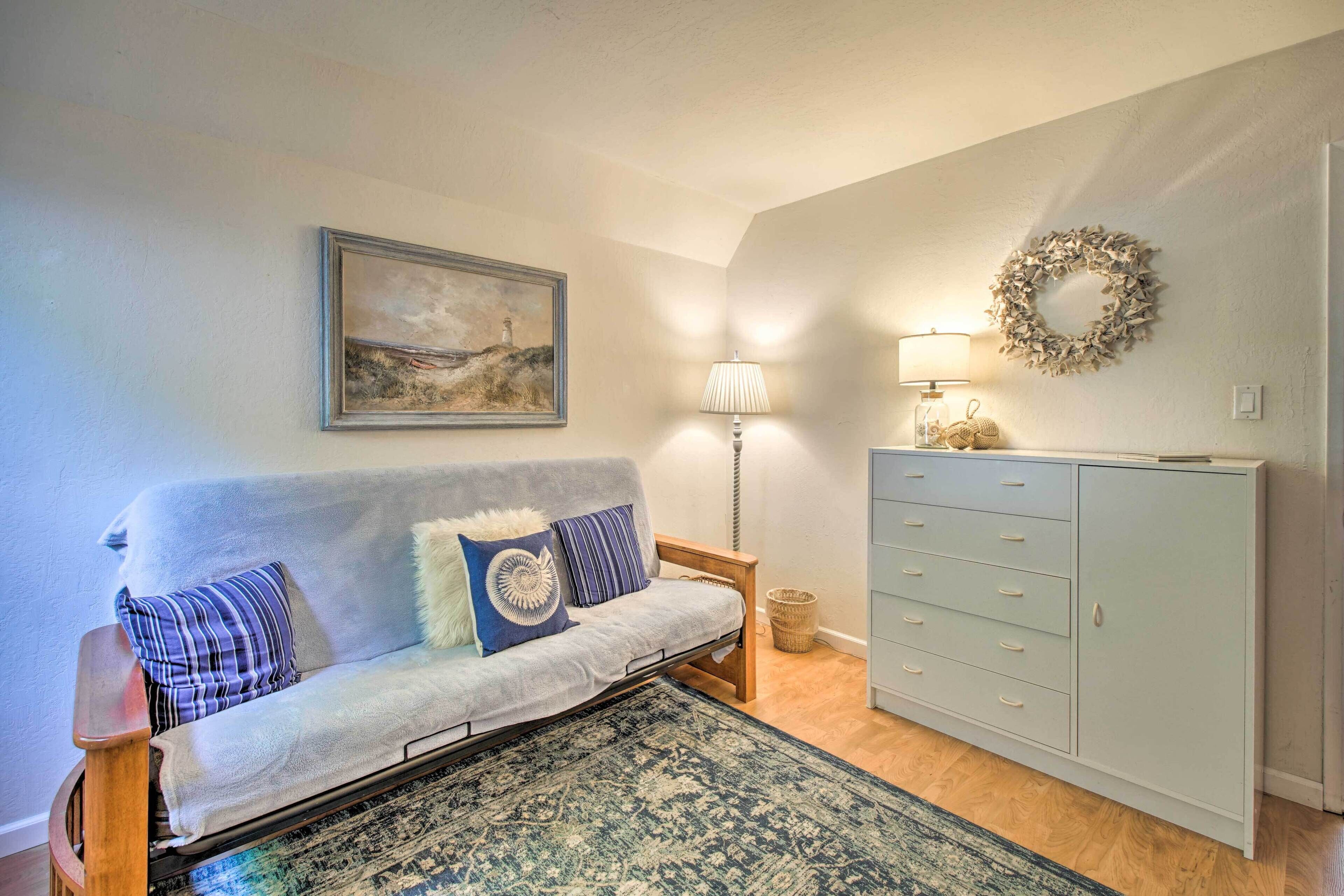 Um quarto com sofá, luminária, cômoda, tapete e um ornamento na parede.