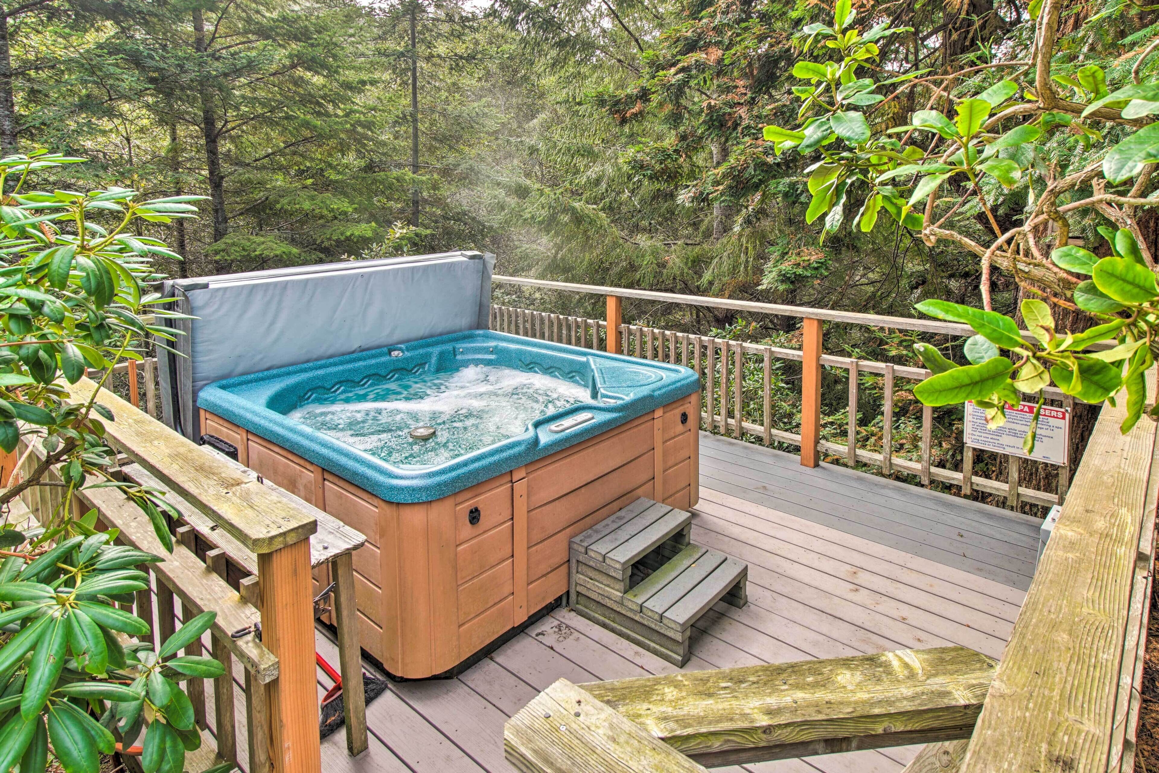 A hot tub on a wooden deck surrounded by lush greenery.