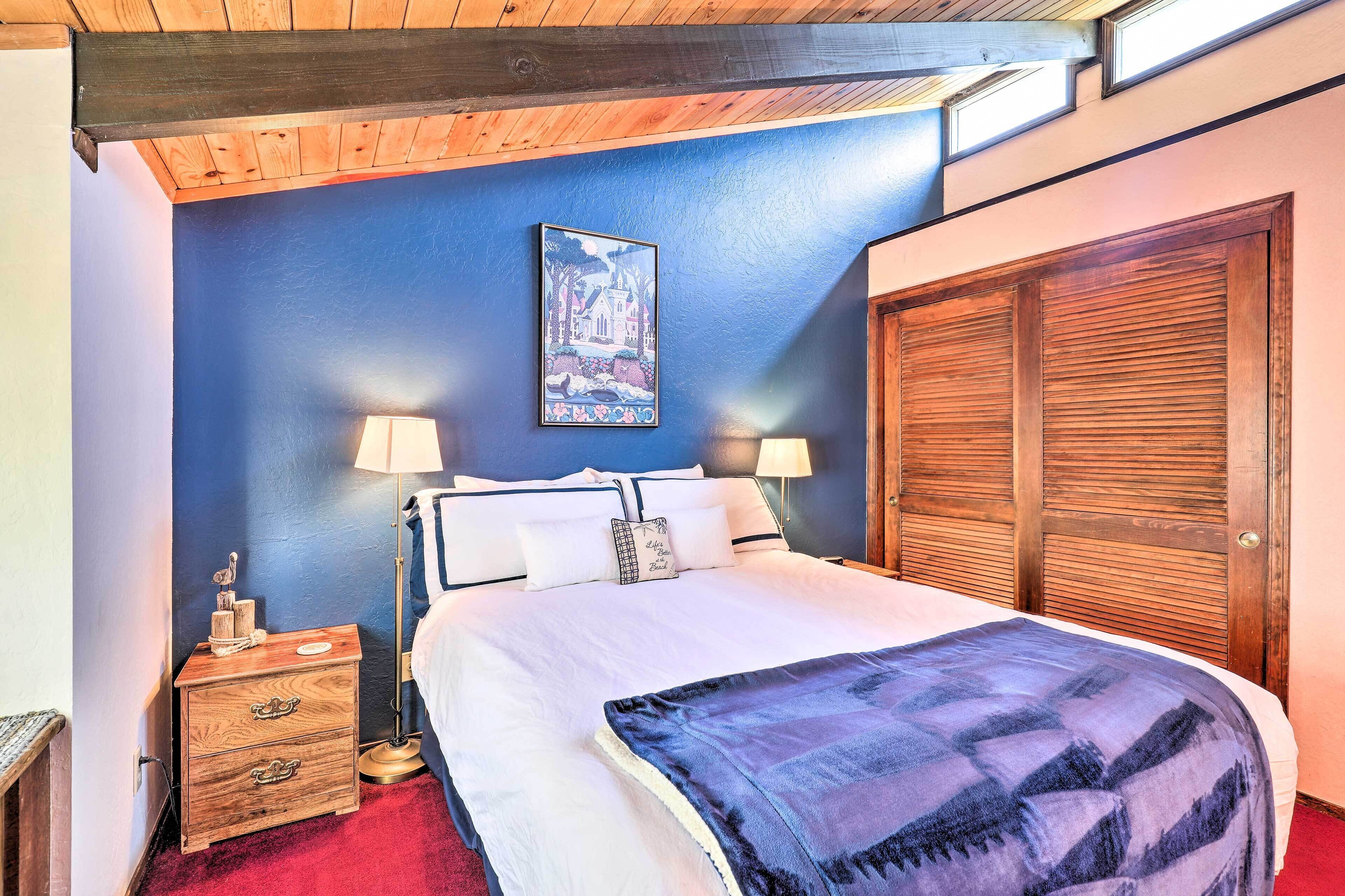 A bedroom with a large bed, wooden headboard, and a blue accent wall.