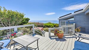 A wooden deck with outdoor furniture, a potted plant, and a view of the ocean. - Oceanfront Irish Beach 'sea Haven' Home w/ Hot Tub (Manchester)