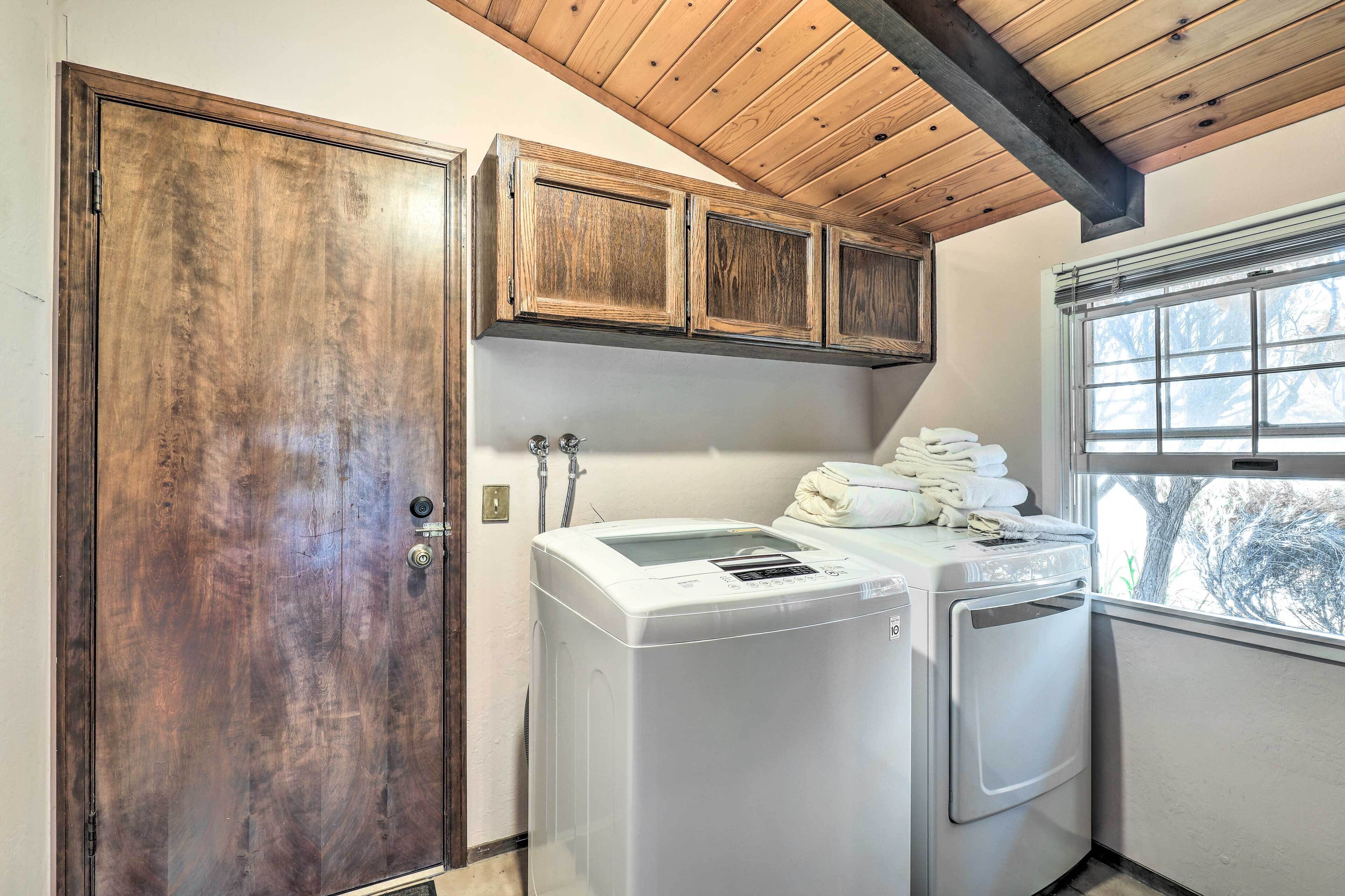 A laundry room with wooden cabinets, a washing machine, and a dryer.