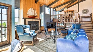 A spacious living room with a fireplace, a bookshelf, and a large window. - Oceanfront Irish Beach 'sea Haven' Home w/ Hot Tub (Manchester)