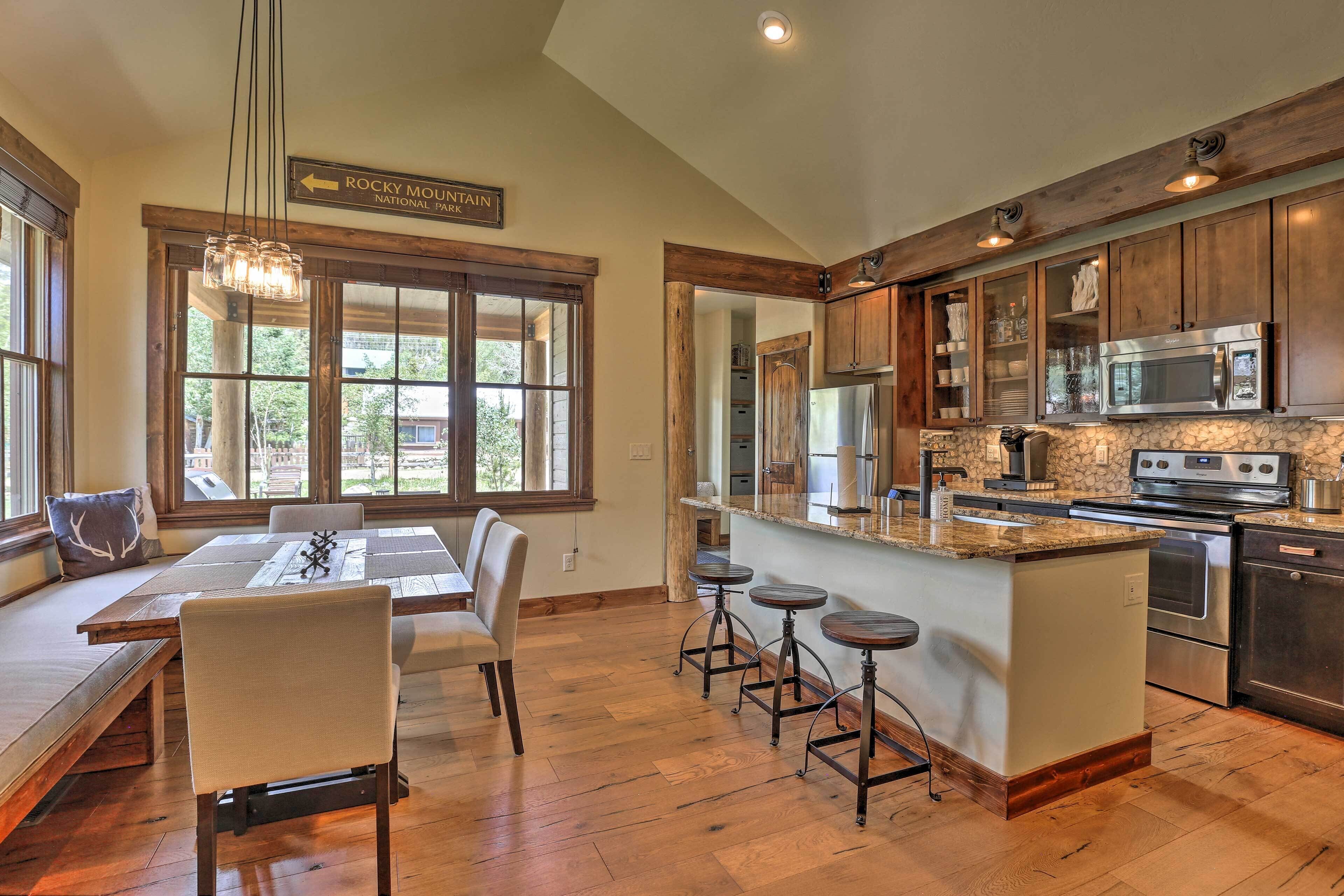 A spacious kitchen with wooden cabinets, a large island with stools, and a view of Rocky Mountain National Park.