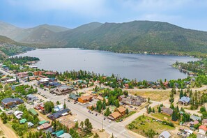 An aerial view of a lakeside town with residential buildings, roads, and a large body of water surrounded by mountains. - Walk to Main St & Marina: Grand Lake Cabin! (Grand Lake)