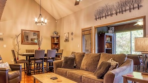 A cozy living room with a sofa, coffee table, and dining area. - Cozy Cabin w/ Mountain Views Near Skylift Park! (Gatlinburg)
