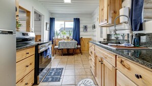 Una cocina con armarios de madera, encimera de granito y comedor con mesa y sillas.
