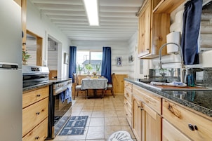Una cocina con armarios de madera, encimera de granito y comedor con mesa y sillas.