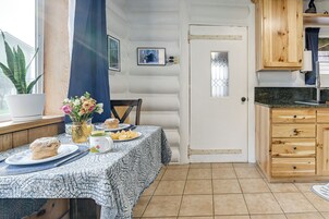 Una cocina acogedora con una mesa dispuesta para el desayuno, armarios de madera y una ventana con una planta.