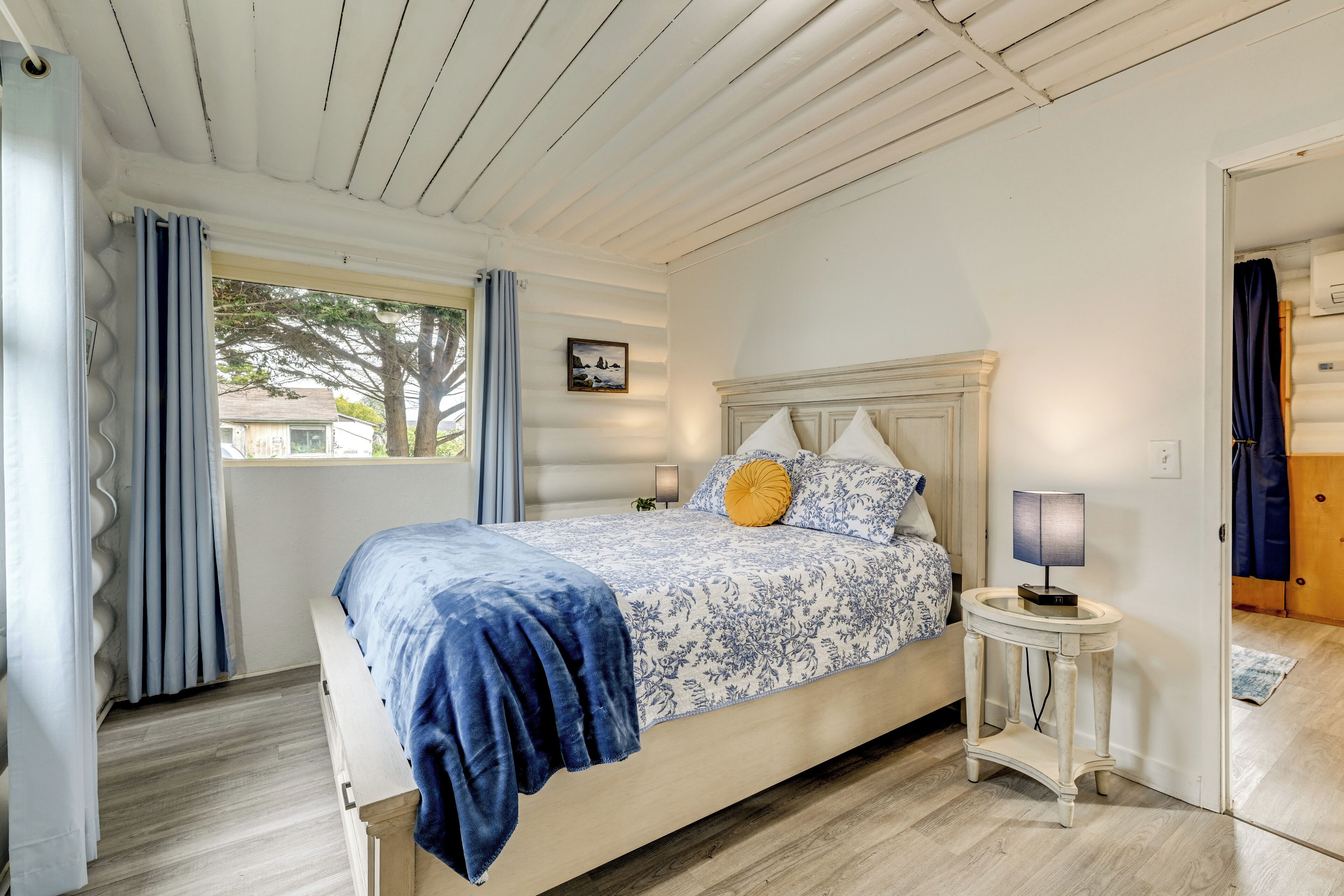A bedroom with a bed, a nightstand, a lamp, and a window with curtains.