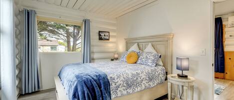 A bedroom with a bed, a nightstand, a lamp, and a window with curtains.