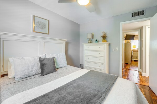 A bedroom with a bed, a dresser, a ceiling fan, and a framed picture on the wall.