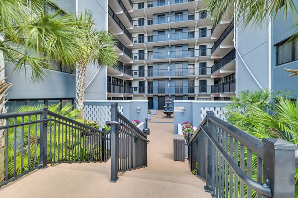 Un edificio residencial de varios pisos con balcones, un patio central y una escalera.