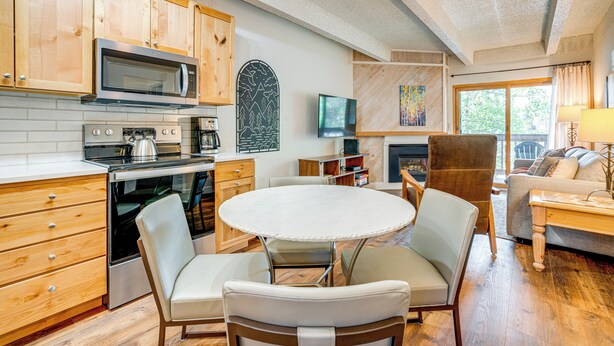 Una cocina moderna con armarios de madera, un microondas, estufa y un comedor con una mesa redonda y sillas.