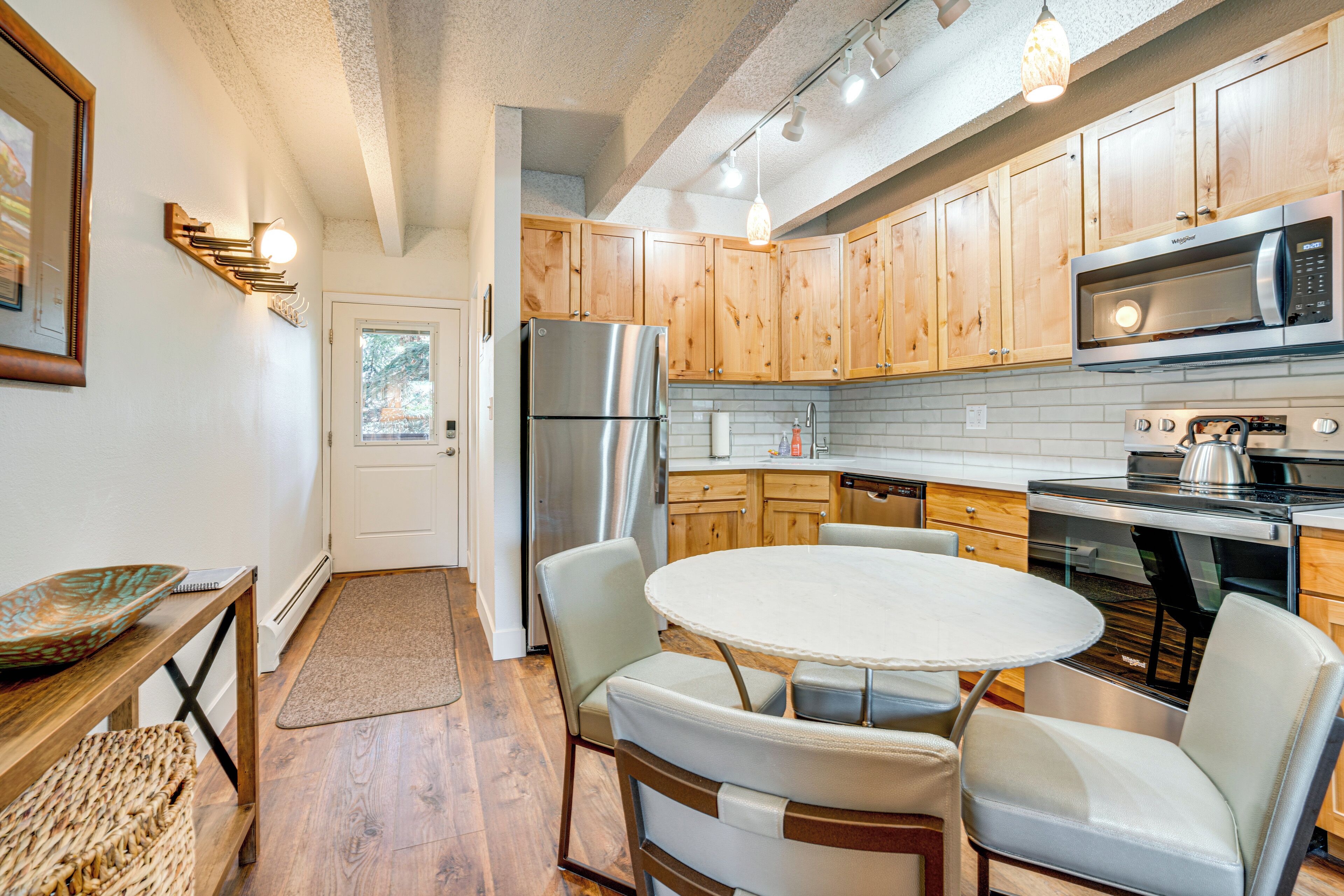A modern kitchen with wooden cabinets, stainless steel appliances, and a round dining table with chairs.