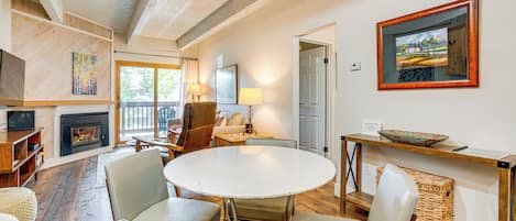 A cozy living room with a fireplace, a round dining table, and comfortable seating.