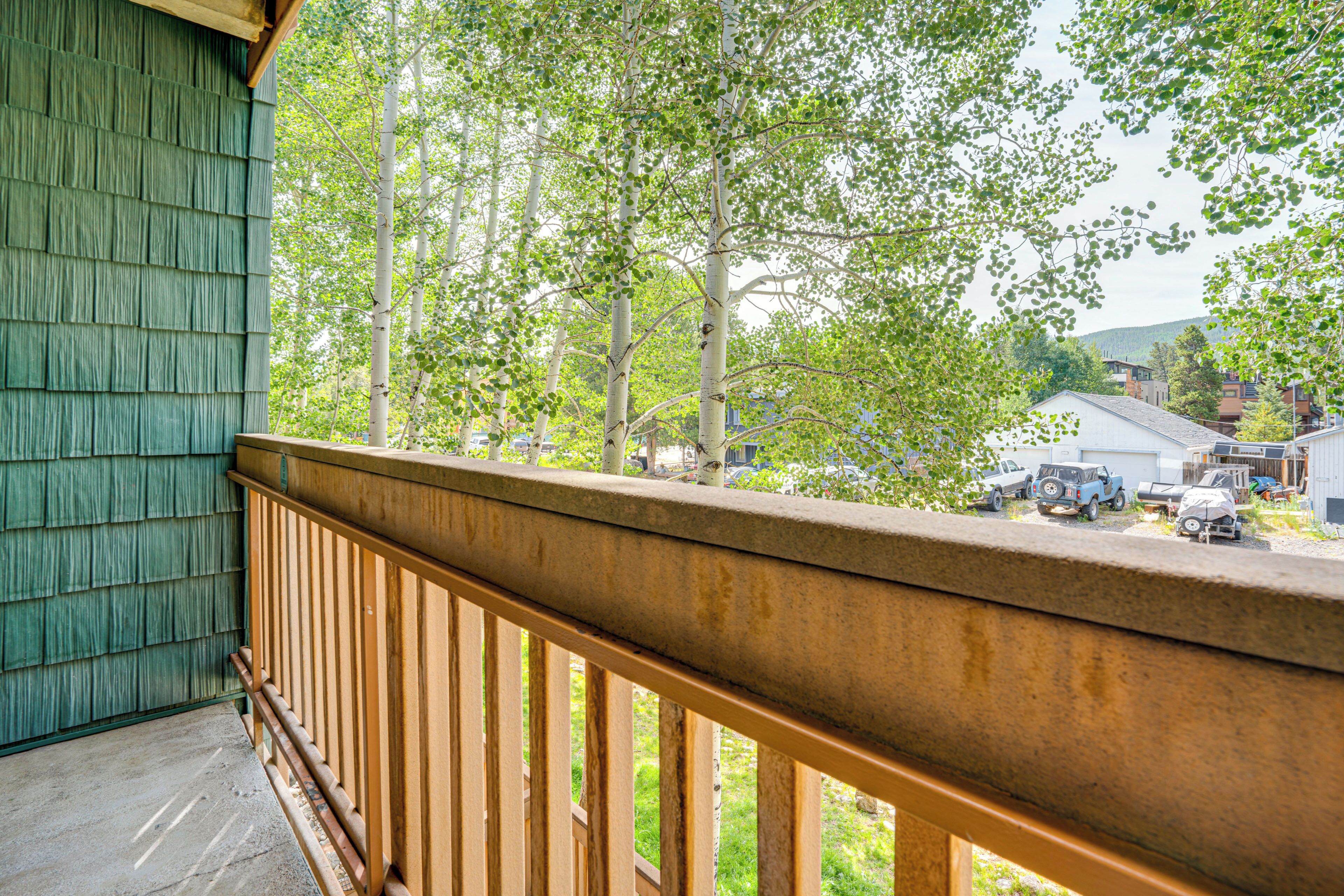 Un balcon en bois offrant une vue sur un quartier résidentiel, avec des maisons et des véhicules stationnés.