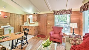 A cozy cabin interior with a wooden dining table, a red armchair, and a kitchen area with wooden cabinets. - Cozy Cottage Duplex: Walk to Peninsula State Park! (Ephraim)