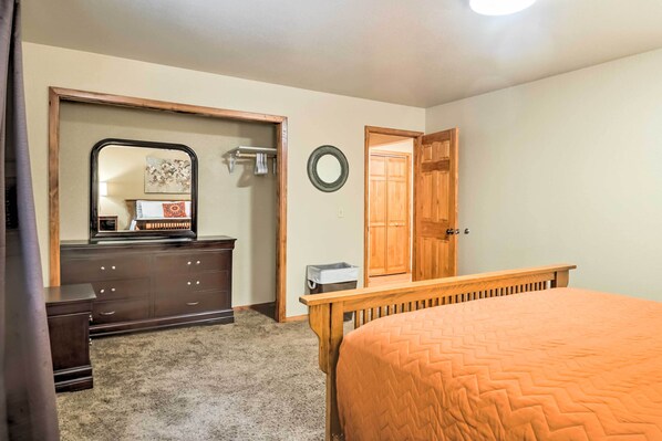 A bedroom with a bed, dresser, mirror, and wooden door.