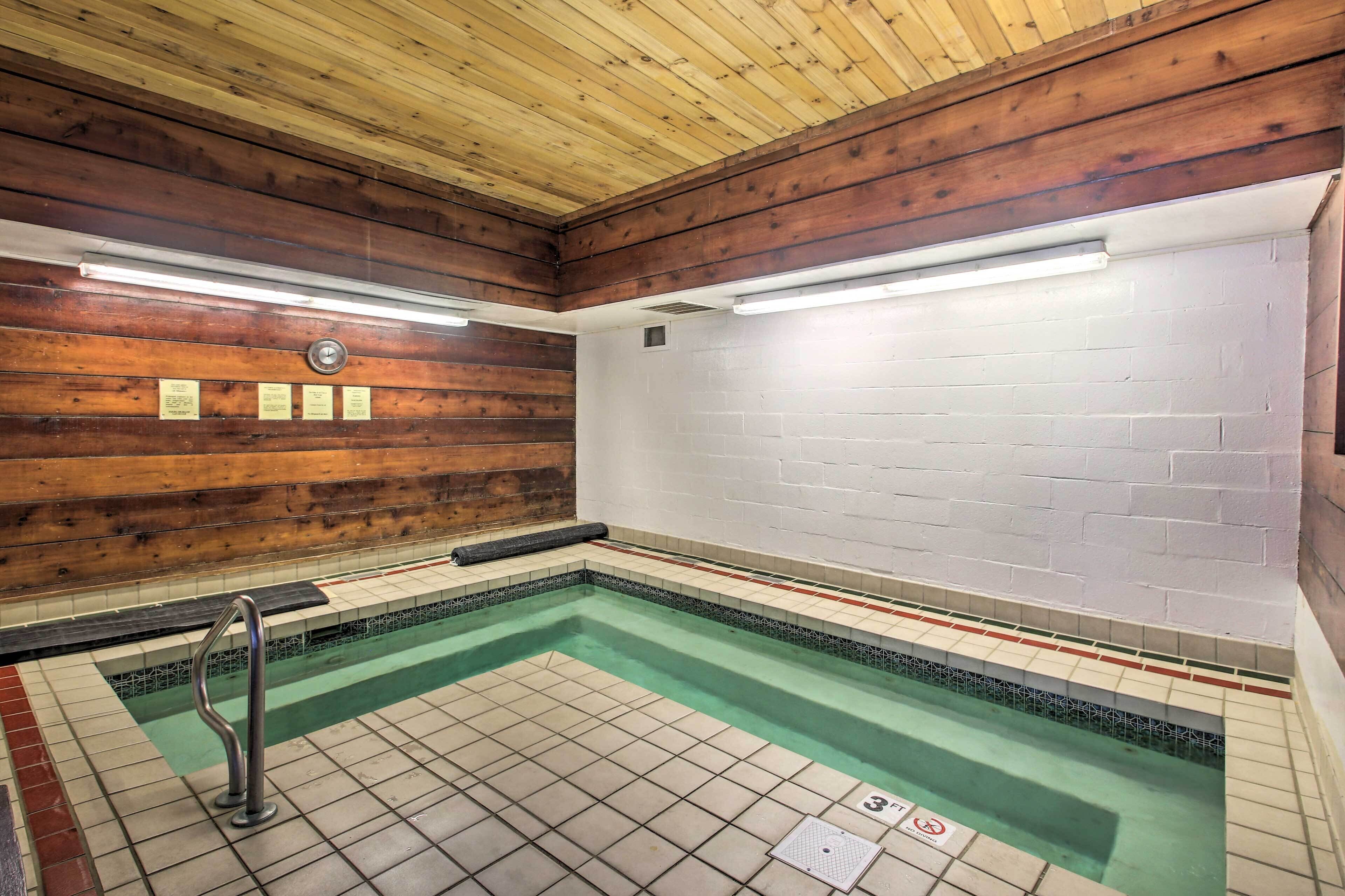 Una pequeña piscina interior con suelo de baldosas y paredes de madera.