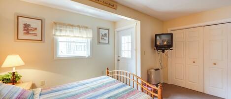 A bedroom with a bed, a television, a door, and a wall-mounted sign.