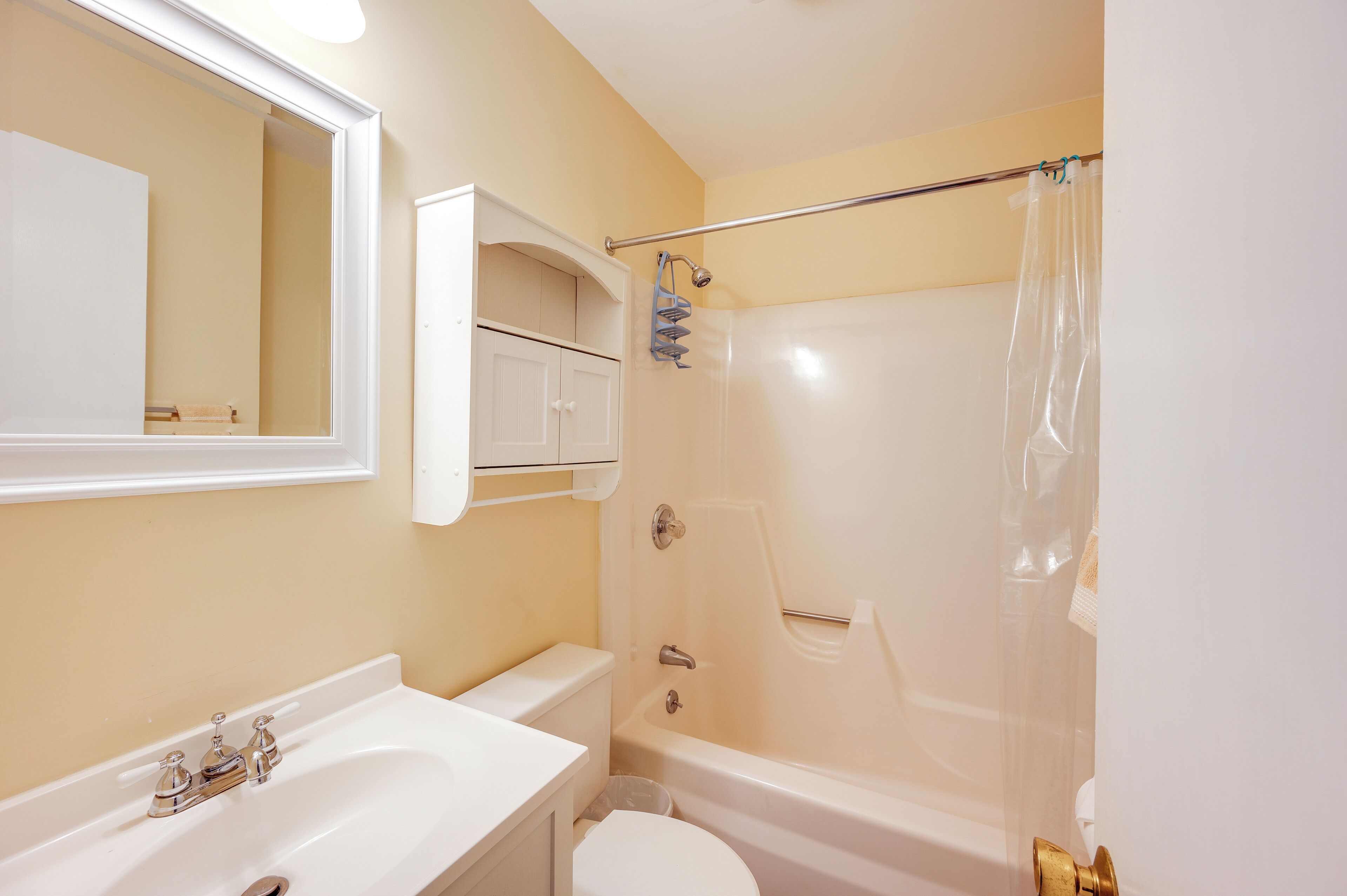 Une salle de bain avec un lavabo, des toilettes et une baignoire, le tout de couleur blanche.