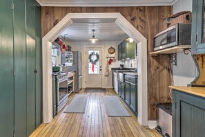 A kitchen with wooden floors, a stove, refrigerator, microwave, and cabinets.
