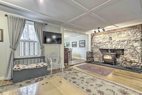 A cozy living room with a stone fireplace, a comfortable bench, and a television mounted on the wall.
