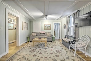 A cozy living room with a sofa, a coffee table, and a patterned rug. - Charming Sutton Cottage: Walk to Lake & Farm! (Sutton)