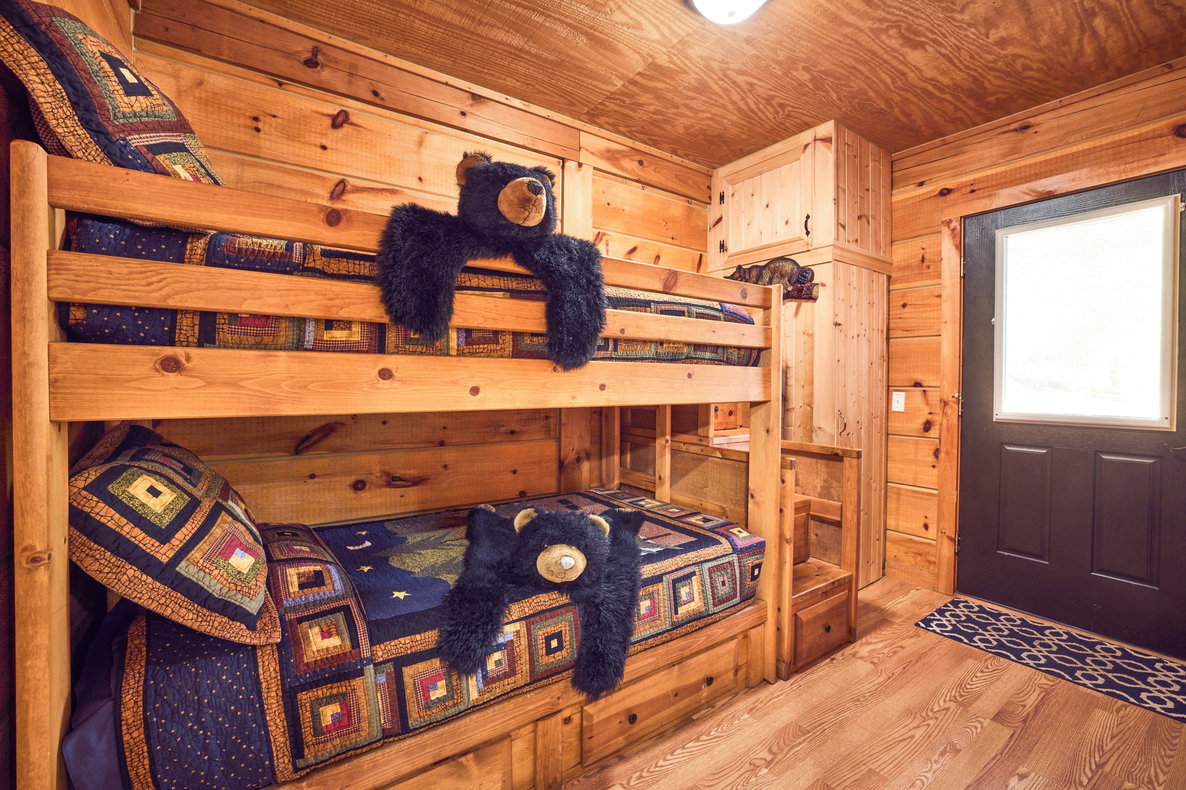 A wooden bunk bed with quilts and a teddy bear.