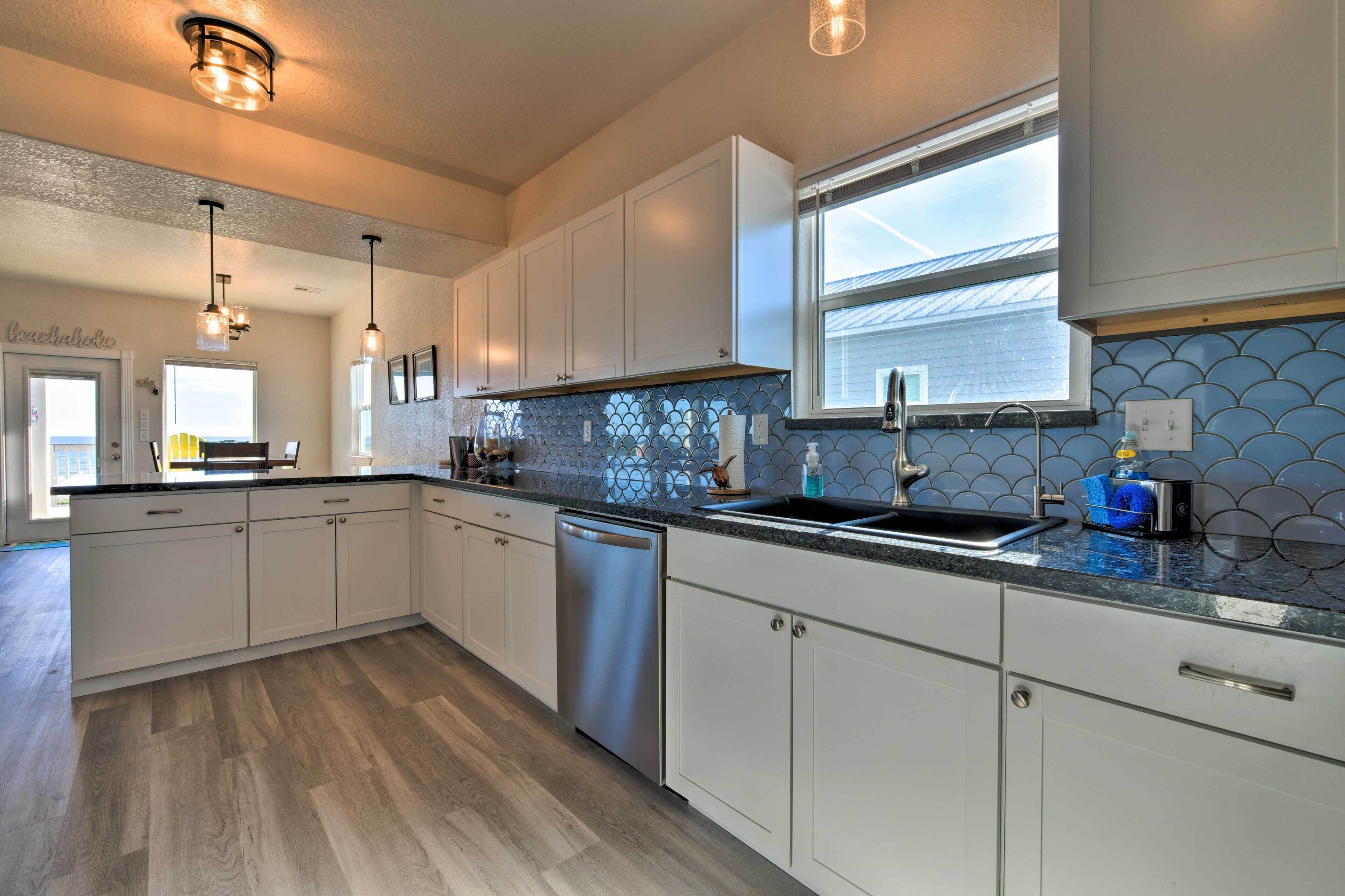 A modern kitchen with white cabinets, a stainless steel dishwasher, and a blue-tiled backsplash.