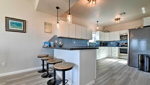A modern kitchen with a central island, bar stools, and stainless steel appliances. - 'sea Shell Chalet': Oceanfront Surfside Beach Gem (Freeport)