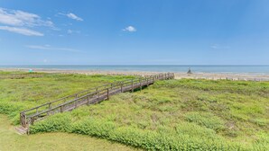 A wooden boardwalk leading to a beach with a clear sky. - 'sea Shell Chalet': Oceanfront Surfside Beach Gem (Freeport)