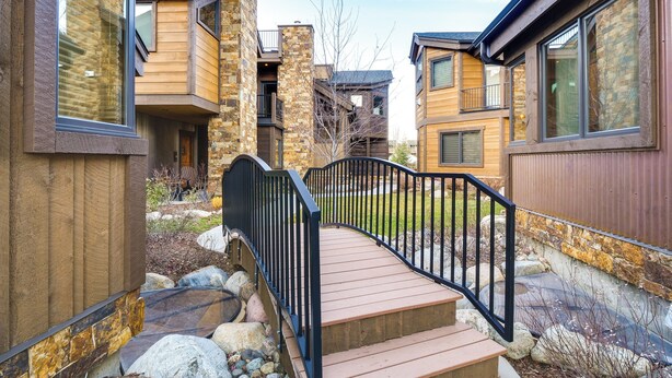 A modern residential building with a wooden deck, stone accents, and a black metal railing. - Frisco Condo w/ Rooftop Deck: Walk to Main St! (Frisco)