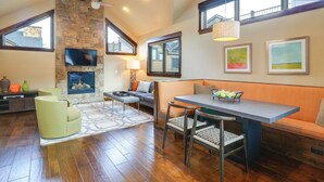 A spacious living area with a stone fireplace, a dining table with chairs, a sofa, and artwork on the walls. - Frisco Condo w/ Rooftop Deck: Walk to Main St! (Frisco)